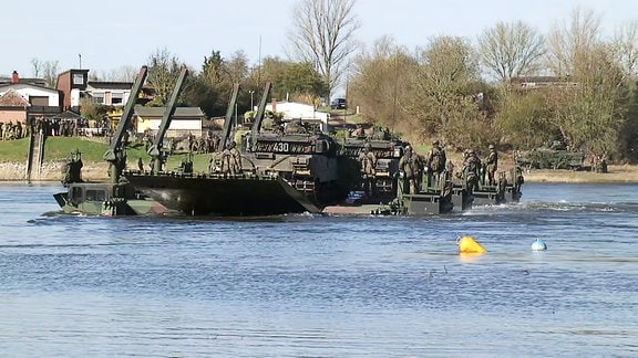Während einer Bundeswehr Übung wird schweres Gefährt über einen Fluss befördert.