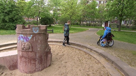 Kind im Rollstuhl auf einem ungeeigneten Spielplatz