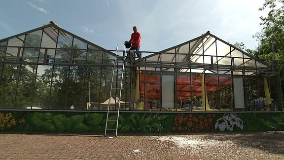 Ein Mann vefreit das Dach eines Gartencenters vom restlichen Eis