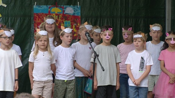 Grundschüler stehen auf einer Bühne und singen