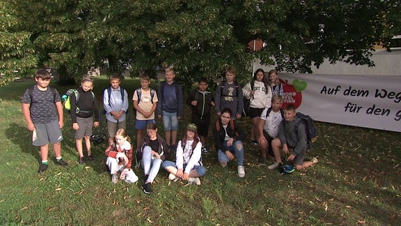 Eine Gruppe Kinder steht und sitzt für ein Gruppenfoto.