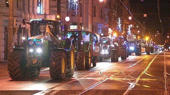 Beleuchtete Traktoren in einer nächtlichen Straße