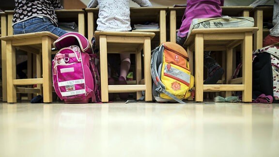 Zwei Schulranzen stehen auf dem Boden eines Klassenzimmers
