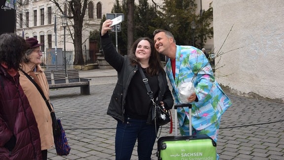 Eine Frau macht ein Selfie mit einem Mann in einem knallbunten Anzug.