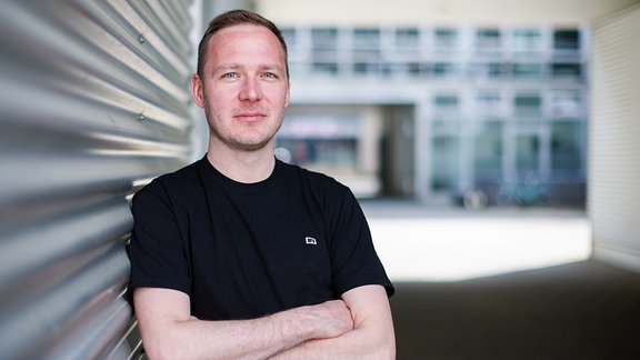 André Herrmann, deutscher Autor, Comedian und Podcaster, steht in einem Leipziger Innenhof.