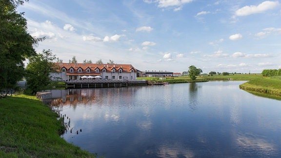 Ein langezogenes Haus steht an einem Fluss.