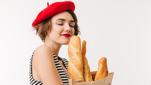 Frau mit roter Mütze riecht an Baguette 