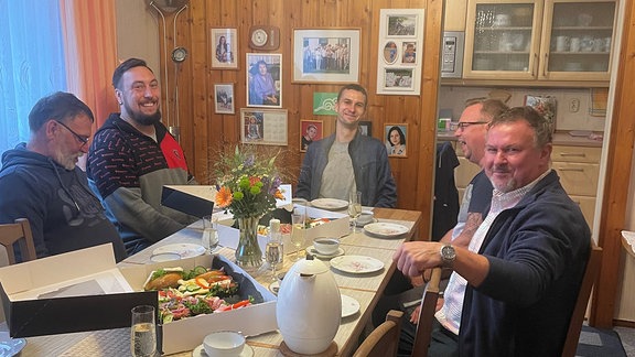 Eine Gruppe Männer sitzen am Tisch.