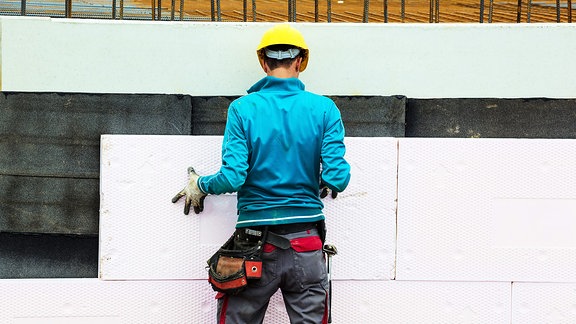 Bauarbeiter verkleidet ein Wand mit einer Platte.
