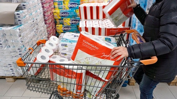 Hamsterkäufe wegen Corona-Virus, Frau kauft große Mengen an Papiertüchern und Klopapier zur Überbrückung einer eventuellen Corona-Pandemie in Deutschland