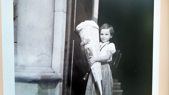 Das Schulanfangsfoto ist aus dem Jahr 1954. Christine Effenberger schreibt dazu: „Wir waren ja Nachkriegskinder und es gab noch nicht all zu viel. Zu meiner Überraschung bekam ich eine riesengroße Zuckertüte. Wie das meine Eltern angestellt hatten, weiß ich nicht. Ich war mächtig stolz.“ 