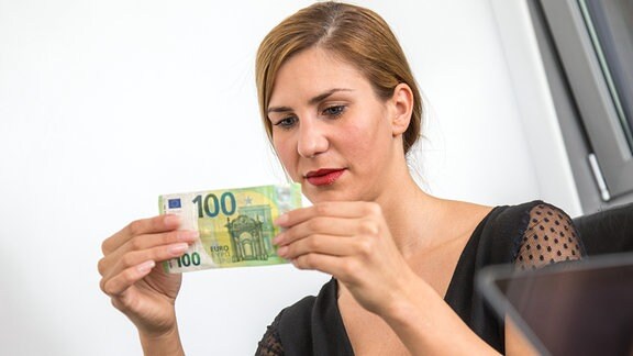 Illustration - Eine Frau hält einen 100 Euro Geldschein in der Hand.