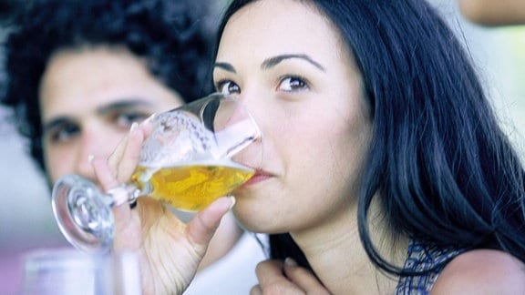 Eine Frau trinkt ein Bier.
