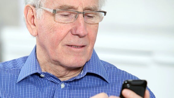 Ein älterer Mann mit einem Smartphone in der Hand.