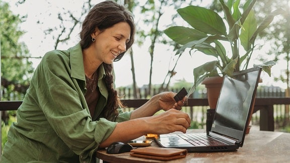 Lächelnde Geschäftsfrau nutzt Laptop und Kreditkarte