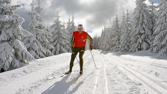 Mann im schneebedeckten Wald beim Langlauf