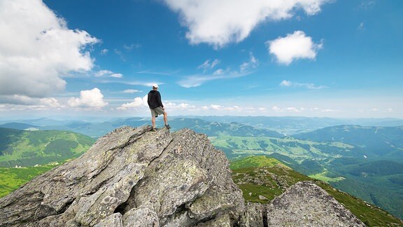 Ein Mann steht auf einem Berggipfel
