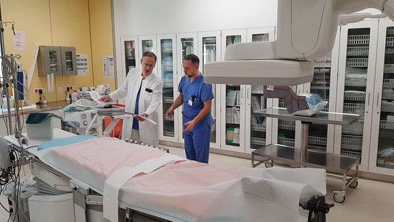 Ein Arzt und ein Krankenpleger bei der Arbeit in einem Untersuchungsraum im Krankenhaus.