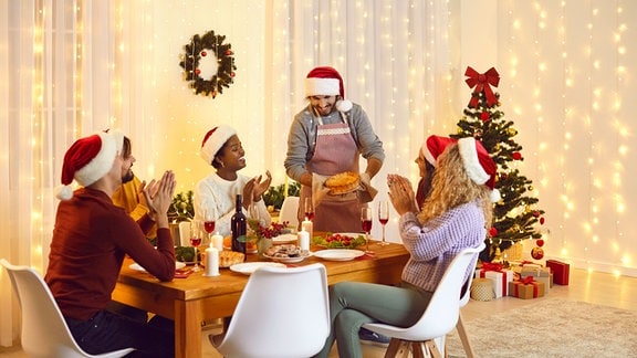 Eine Gruppe Erwachsener sitzt um einen weihnachtlich geschmückten Tisch.