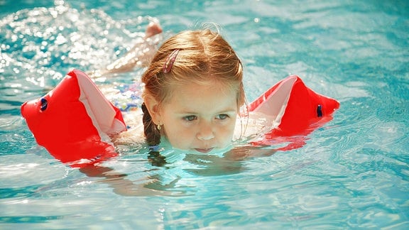 Ein Kind mit Schwimmarmen im Wasser.