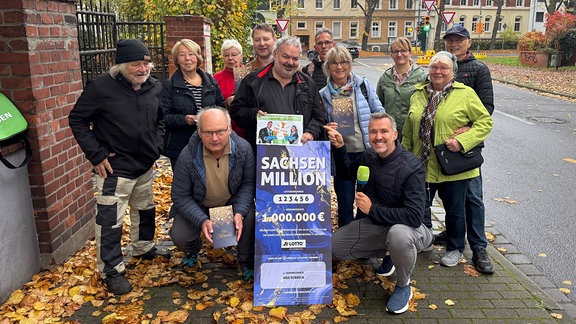 Eine Gruppe Menschen steht um Silvio Zschage und ein Poster mit der Aufschrift "Sachsen Million".