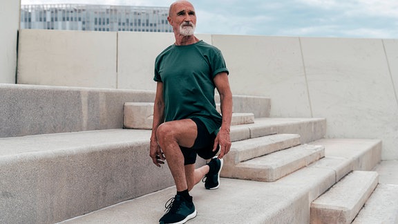Symbolbild: ein älterer Sportler macht Dehnübungen auf einer Treppe