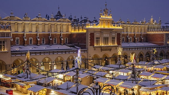 Der schneebedeckte Weihnachtsmarkt in Krakau am Abend.