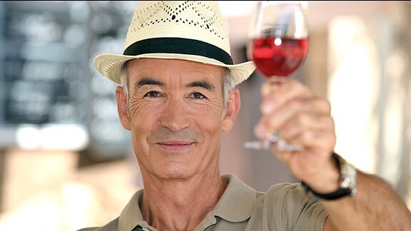 Ein Mann mit einem Glas Rotwein in der Hand