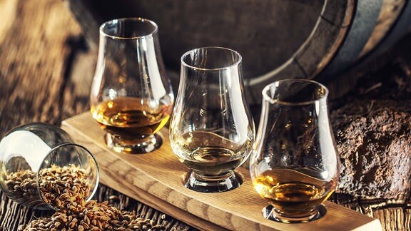 Drei Whiskygläser vor einem Whiskyfass