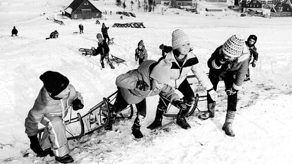 Winterspaß in Altenberg - Kinder ziehen ihre Schlitten zum Rodeln auf einen Hügel.