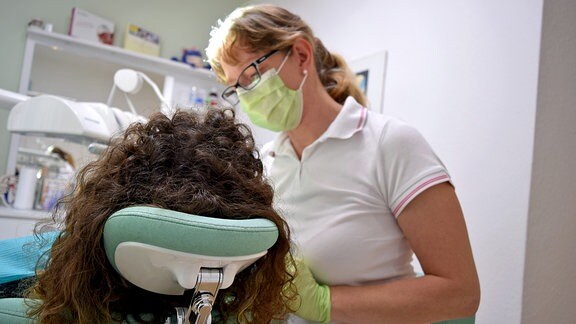 Eine Frau unterzieht ihr Gebiss bei einer Zahnärztin einer Zahnreinigung.