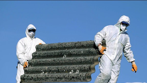 Zwei Männer tragen Asbestplatten.