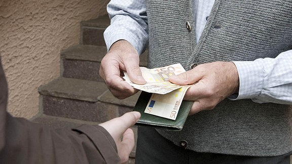 Ein Mann gibt einem Anderen 50-Euro-Scheine