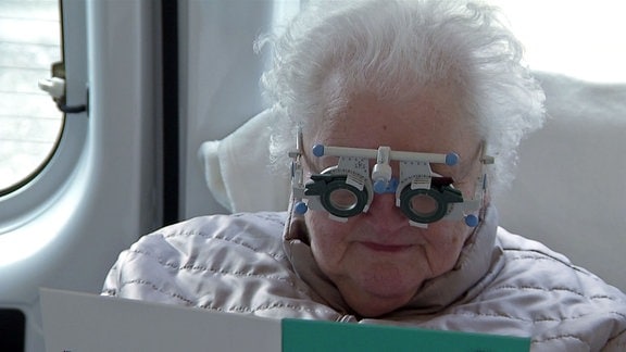 Frau beim Optiker trägt Testgerät.