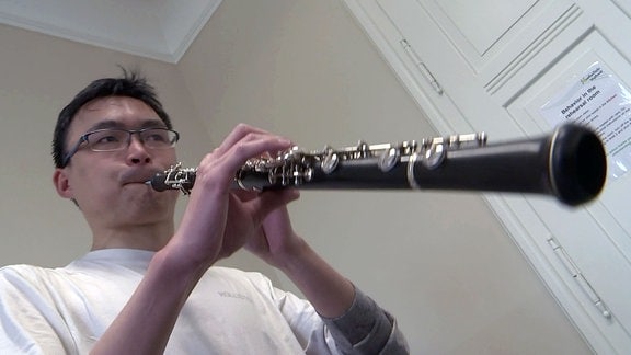 Ein junger Mann spielt auf einer Oboe.