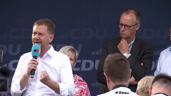 Michael Kretschmer spricht, im Hintergrund Friedrich Merz.