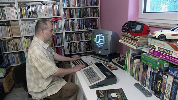 Ein Mann sitzt vor einem alten Computer.