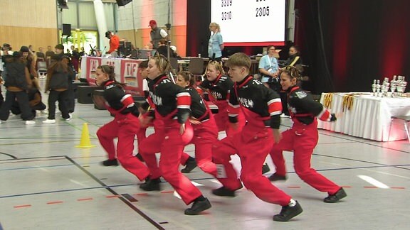 Eine Gruppe Jugendlicher tanzt synchron während eines Wettbewerbs.