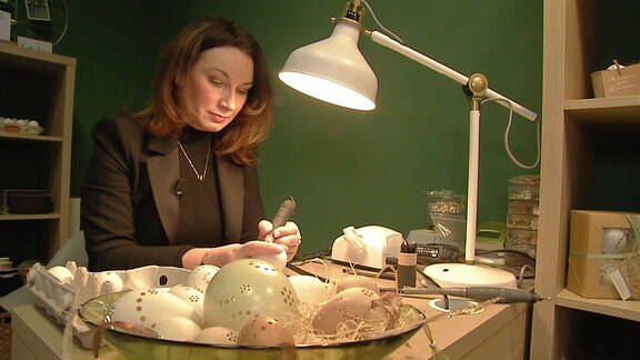 Kati Schmidt stellt an einem Schreibtisch Ostereier her.
