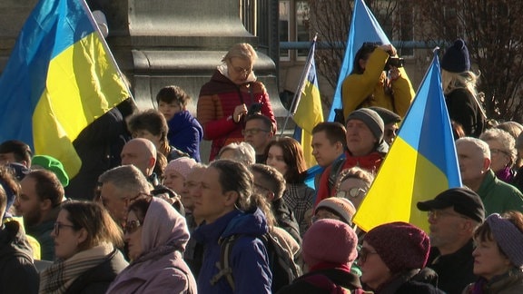 In einer Menschenmenge halten mehrere Menschen Ukraine-Flaggen.