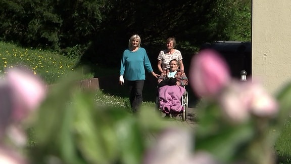 Zwei Schwestern mit ihrer dementen Mutter auf einem Parkgelände