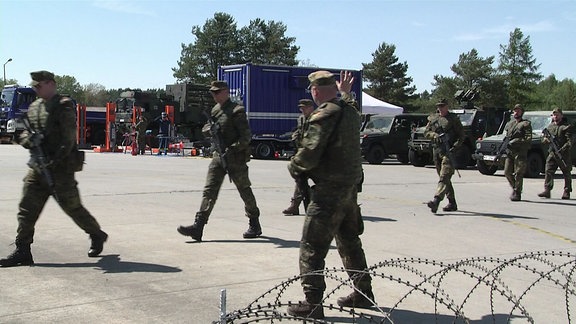 Bundeswehrsoldaten laufen über einen Platz.