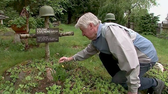Ein mMann kümmert sich auf dem Friedhof in Oberbärenburg um ein Soldatengrab
