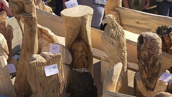 Große, aus Holz geschnitzte Figuren stehen nebeneinander.