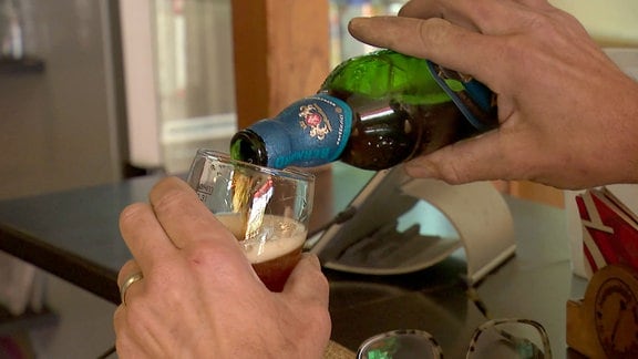 Eine Hand schenkt Bier in ein Glas.