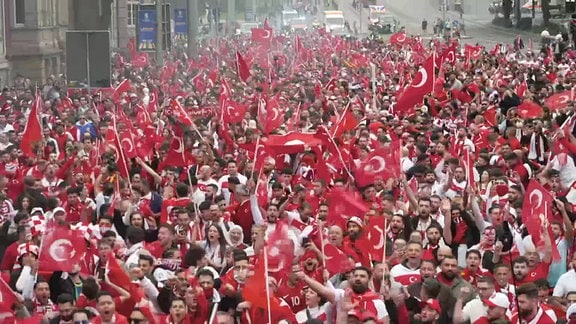 Fans der türkischen Nationalmannschaft laufen über eine Straße.