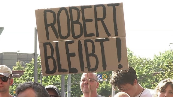 Während einer Demonstration wird ein Schild mit der Aufschrift "Robert bleibt!" hochgehalten.