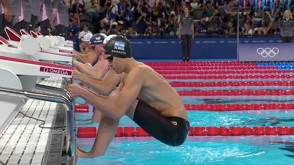 Rückenschwimmer in der Startposition am Startblock.