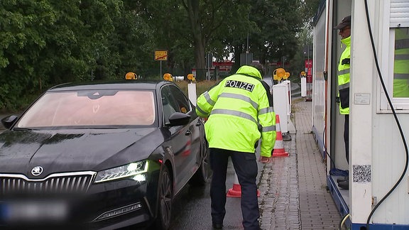 Ein Auto wird kontrolliert von Polizisten