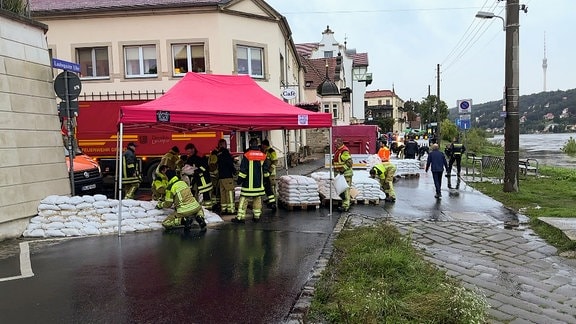 Einsatzkräfte stapeln Sandsäcke 